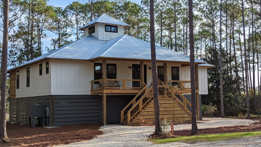 Custom home build by JC Homes & Development on the rural coast of the Florida panhande with metal roofing and custom wood porch