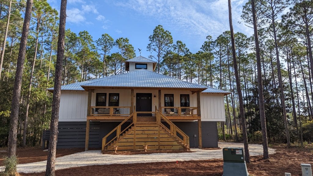 Custom home build by JC Homes & Development on the rural coast of the Florida panhande with metal roofing and custom wood porch